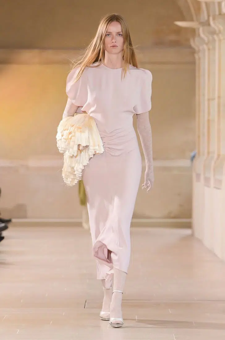 Модель в нежно розовом платье миди с драпировкой на животе от Victoria Beckham