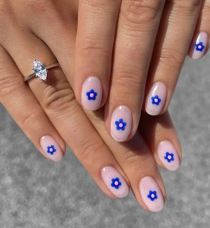 Розовый маникюр с синими цветами по центру на овальных коротких ногтях