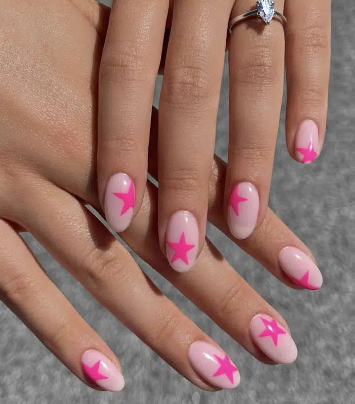 Светлый розовый маникюр с яркими звездами на овальных ногтях средней длины
