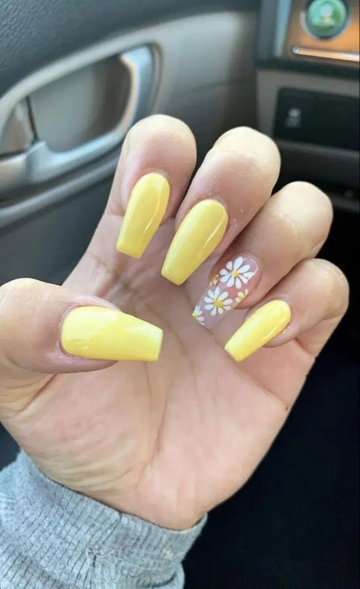 Желтый маникюр с белыми ромашками на указательном пальце на длинных ногтях