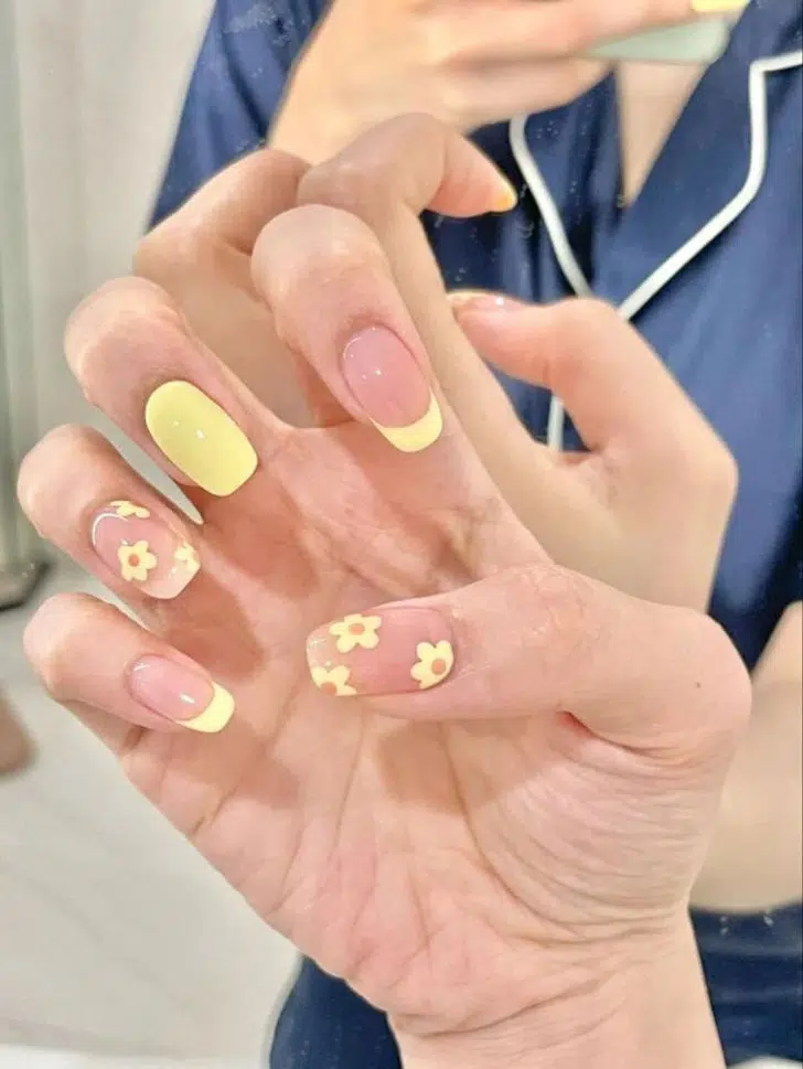 Желтый френч комбинируется с цветочками на ногтях средней длины