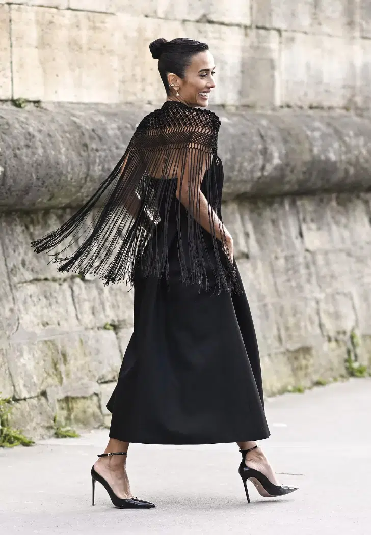 Девушка в черном платье миди, накидке с бахромой и туфлях на ремешке