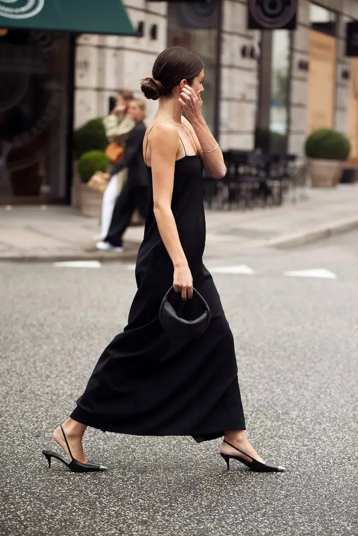 Девушка в длинном черном платье комбинация и туфлях с открытой пяткой на низком каблуке