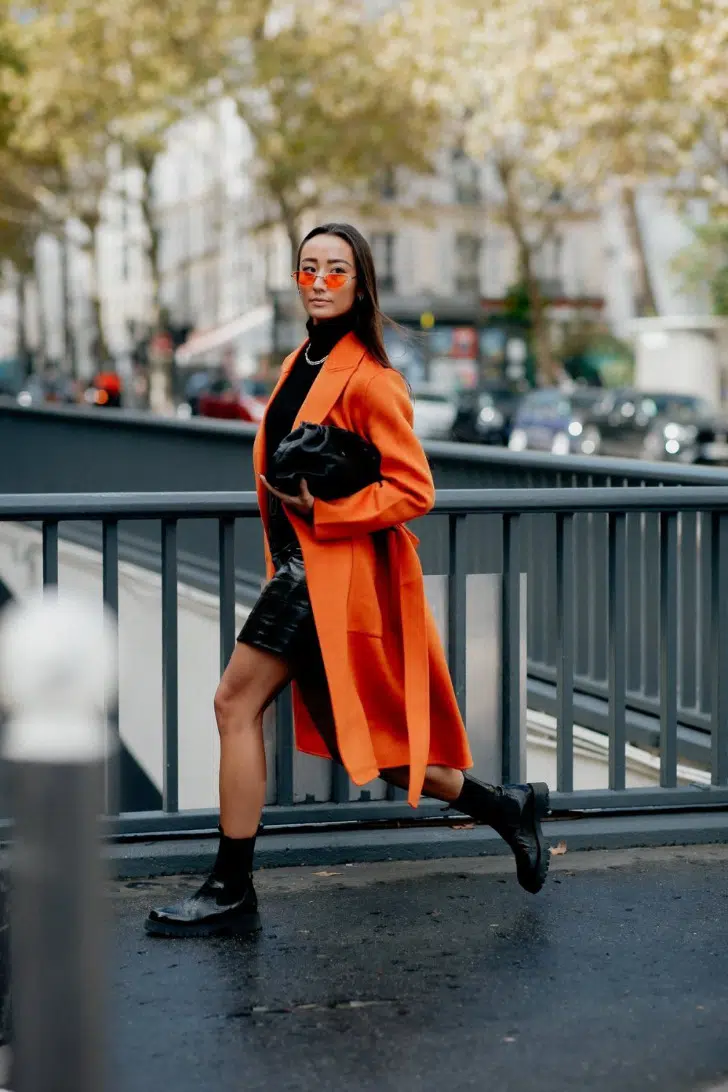 Девушка в оранжевом пальто, лакированных ботинках и с небольшой черной сумочкой