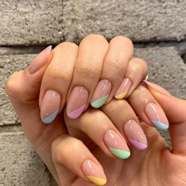 Диагональный разноцветный маникюр в пастельных оттенках на овальных ногтях