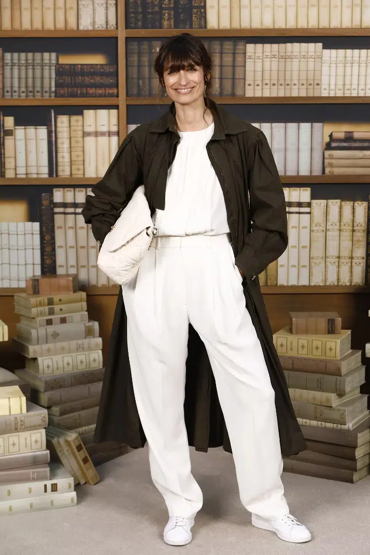 Кэролайн Де Мегре в белых свободных брюках, классическом тренче и белых кедах