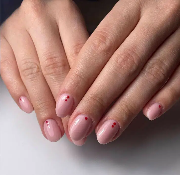 Розовый маникюр с красными точками у основания на коротких овальных ногтях