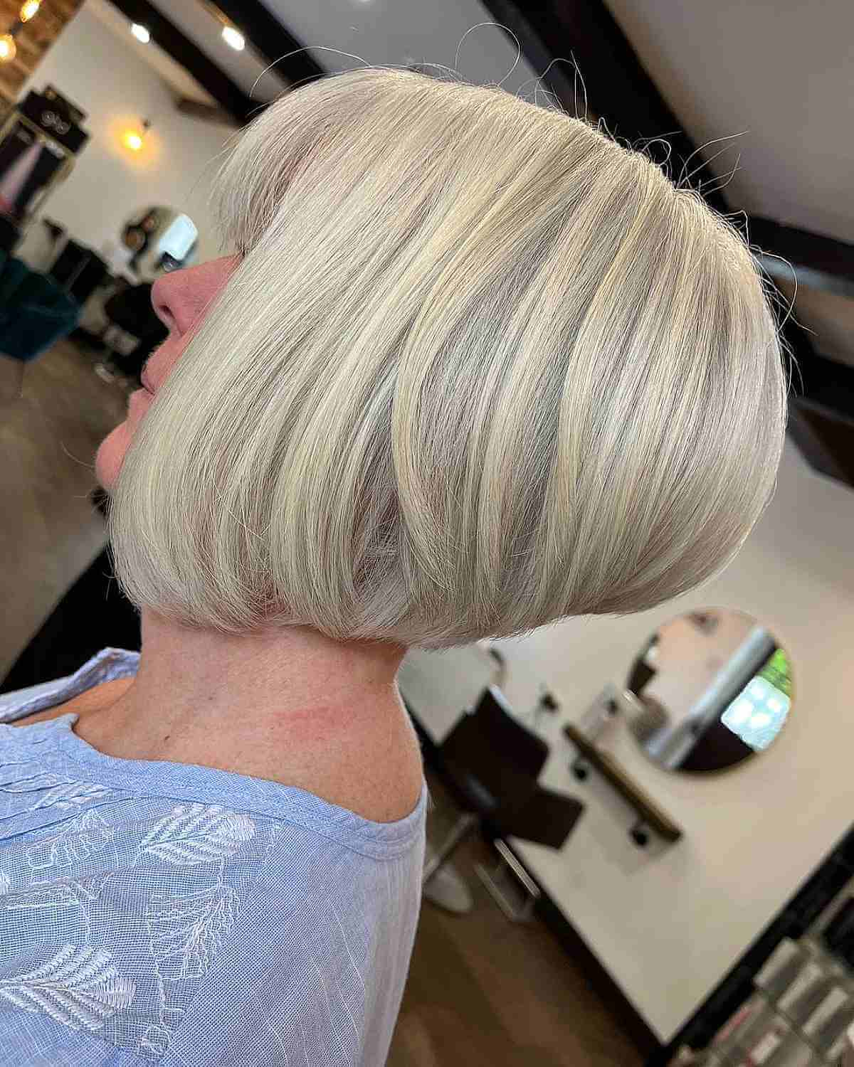 Женщина со стрижкой градуированный боб с челкой на платиновых волосах