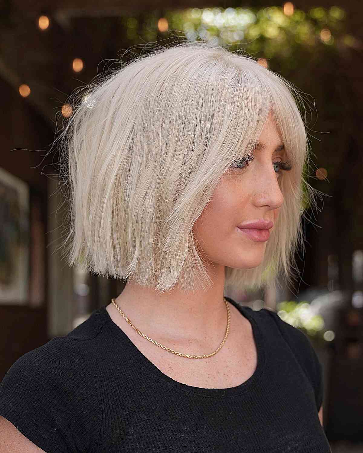 Девушка с текстурированной стрижкой боб с челкой занавеской на платиновых волосах
