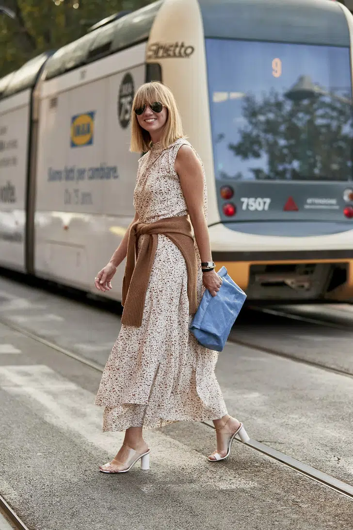 Девушка в легком платье миди с цветочным принтом и виниловых босоножках на разумном каблуке