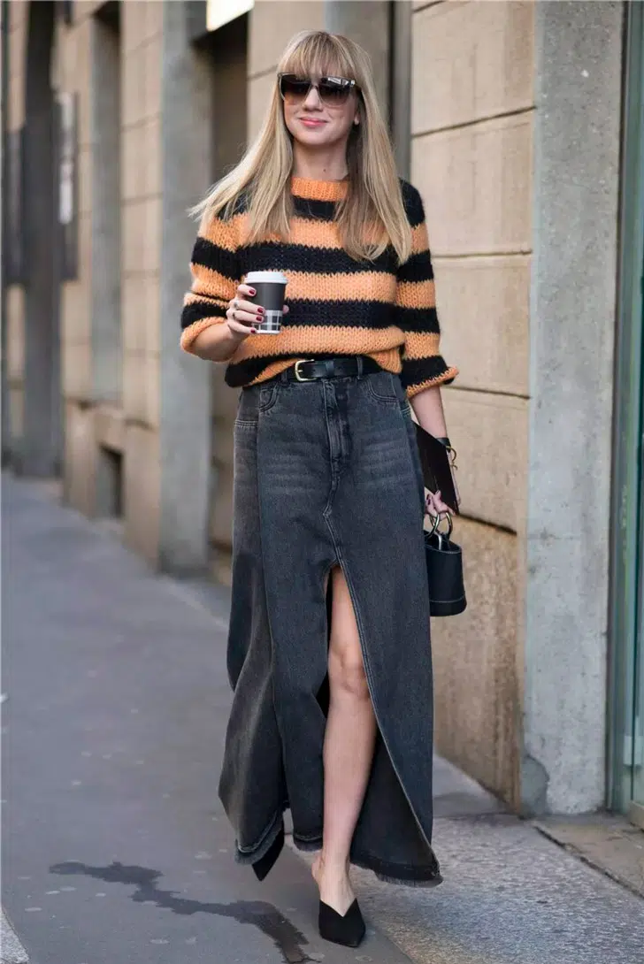 Девушка в полосатом свитере, длинной джинсовой юбке с разрезом спереди и черных туфлях