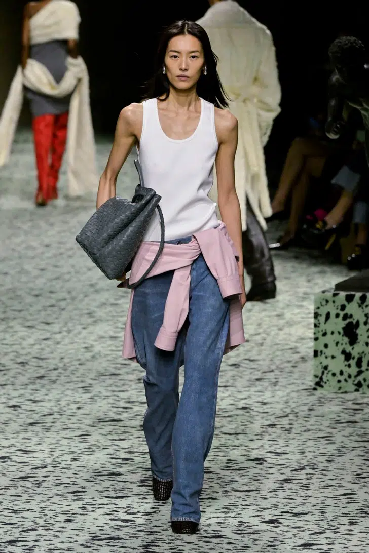 Модель в мешковатых джинсах, белой майке и с серой объемной сумкой от Bottega Venete