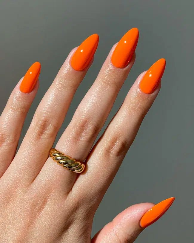 Яркий оранжевый маникюр на длинных острых ногтях