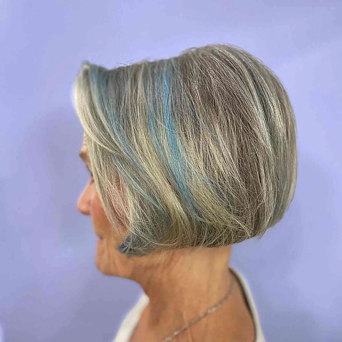 Женщина с объемной стрижкой боб с синими прядями на седых волосах