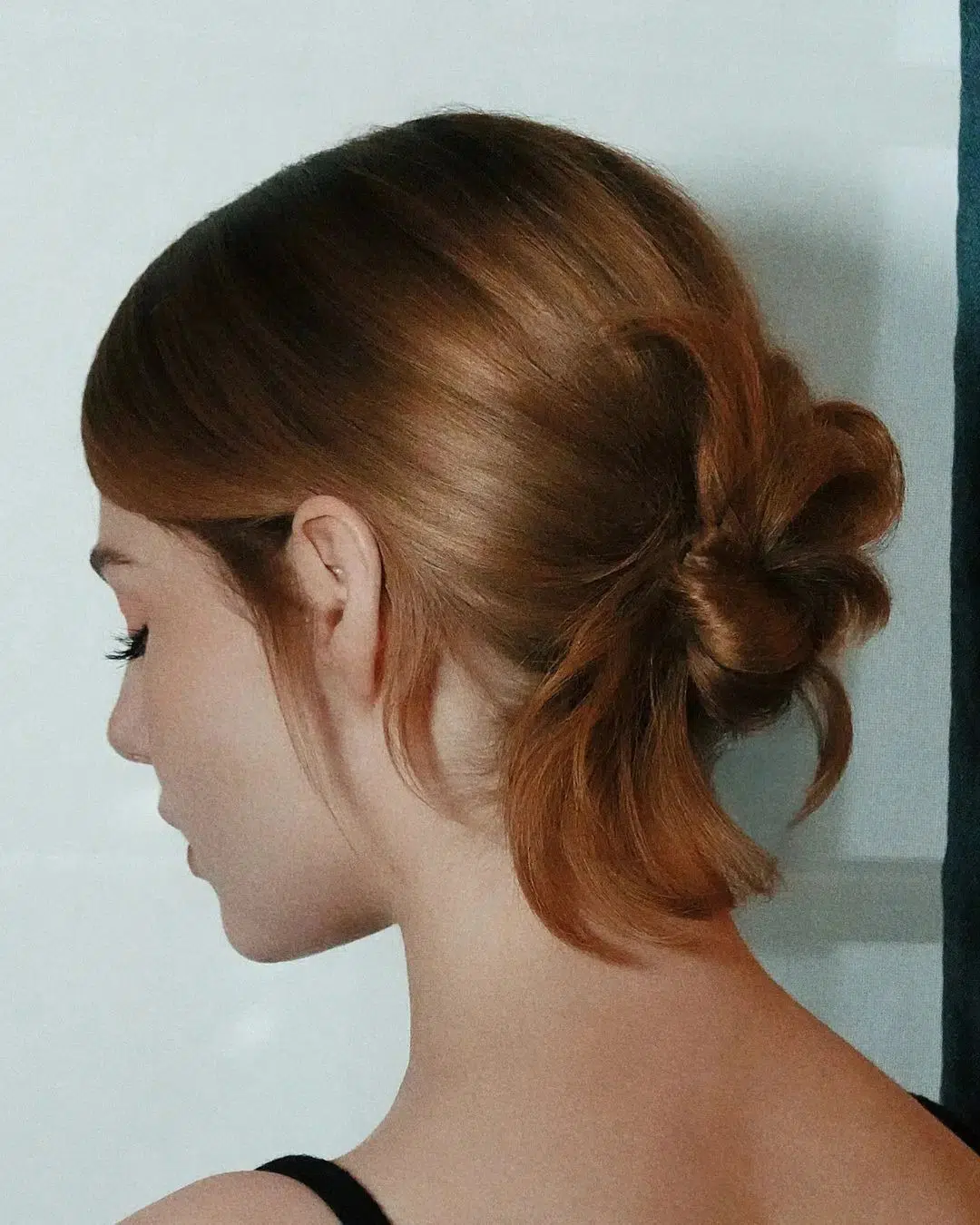 Девушка с гладкими собранными в пучок волосами бронзового оттенка