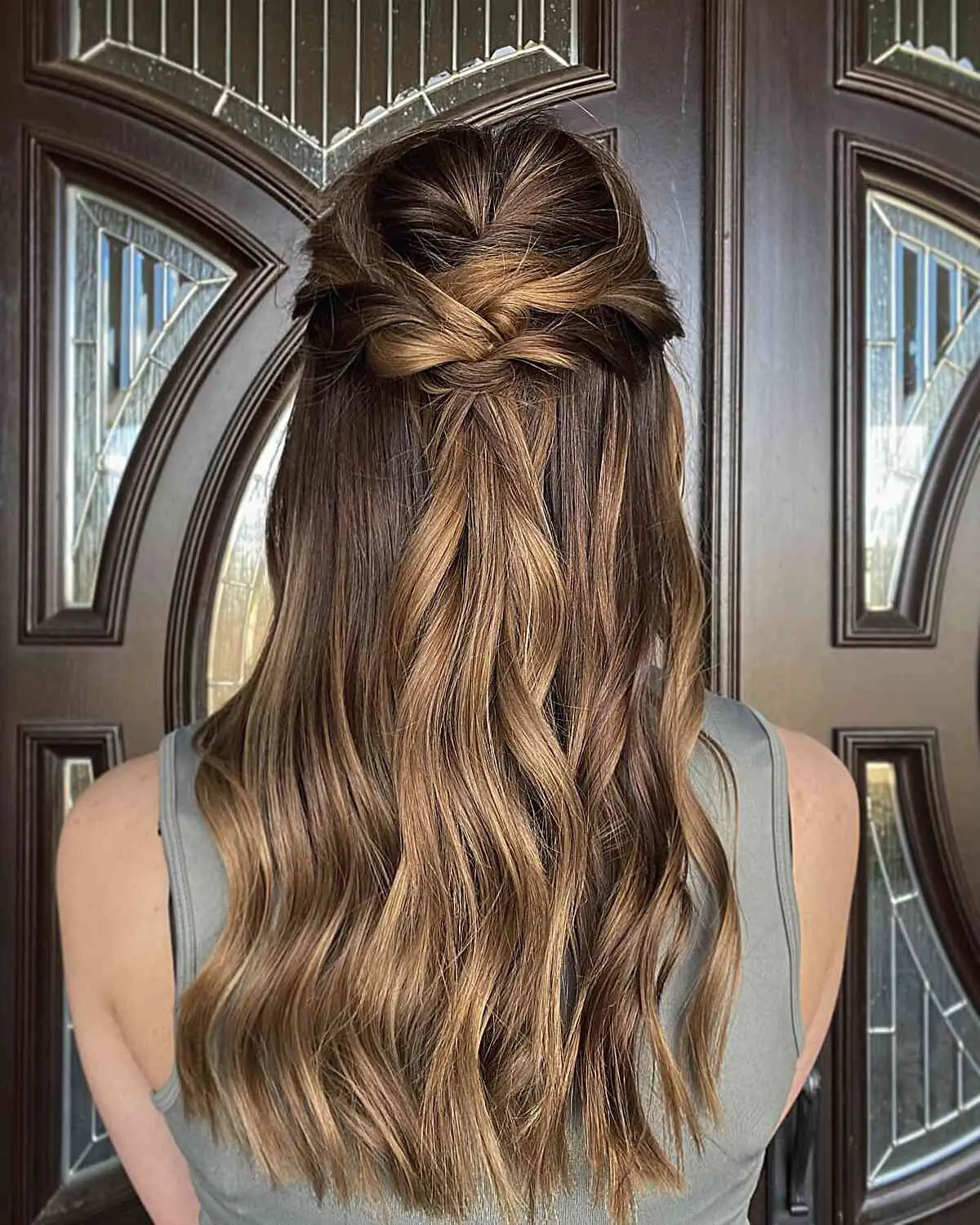 Девушка с полусобранной прической с легкими волнами на блестящих ухоженных волосах