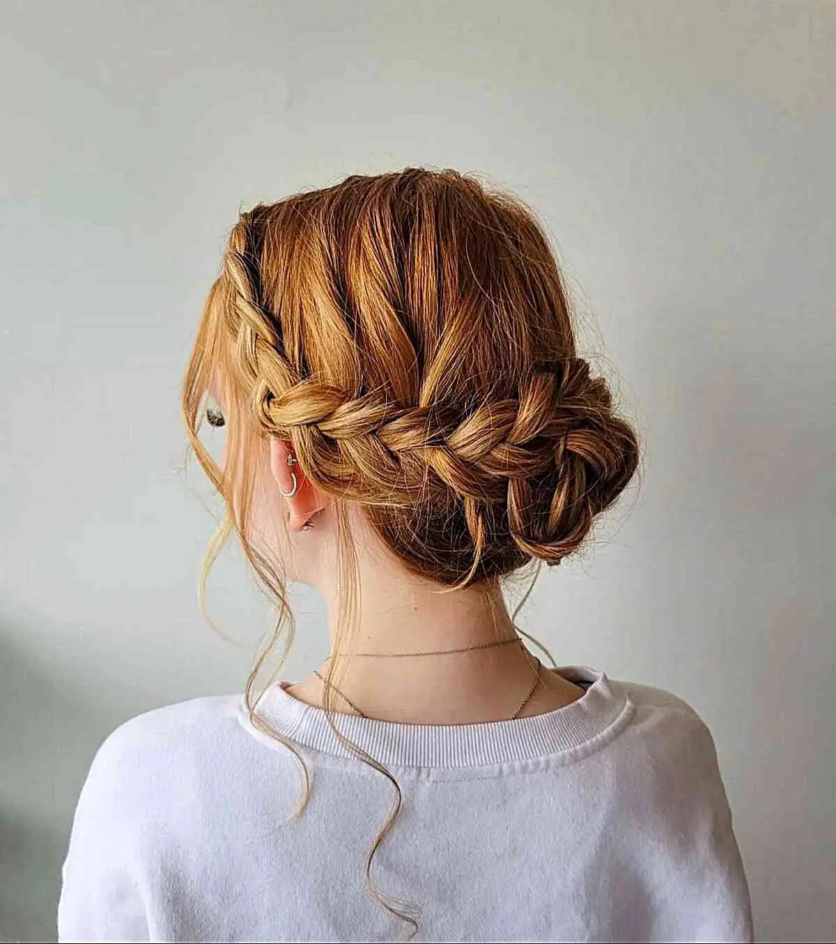 Девушка с собранными волосами с косами и свободными прядями на медных волосах