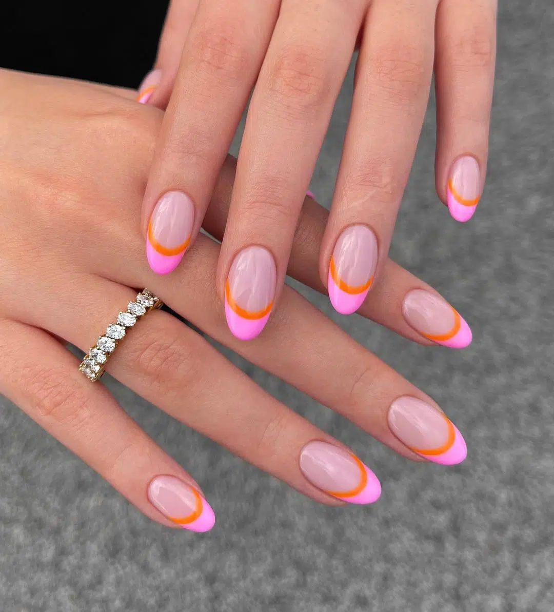 Розовый френч с оранжевой линией на овальных ногтях средней длины