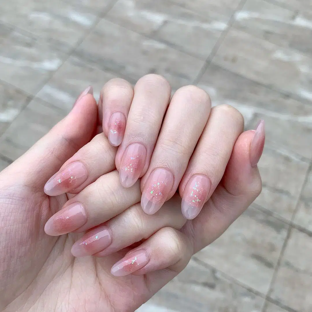 Румяный розовый маникюр с блестками на овальных ногтях средней длины