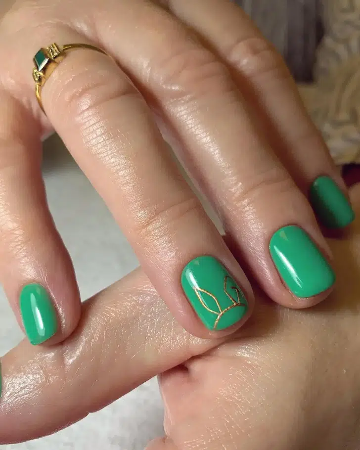 Зеленый маникюр с золотым принтом на коротких ногтях