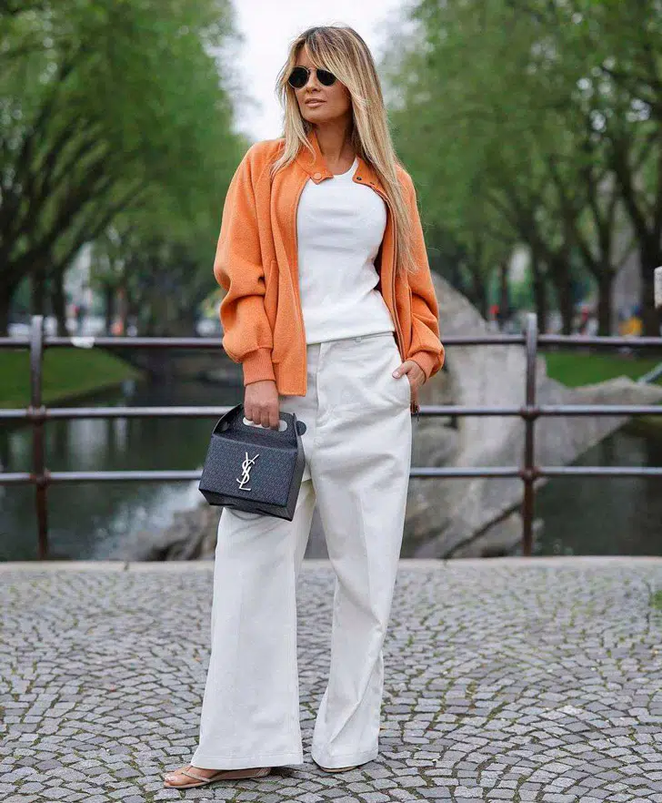 Гитта Банко в свободных белых джинсах, майке и оранжевой кофте оверсайз