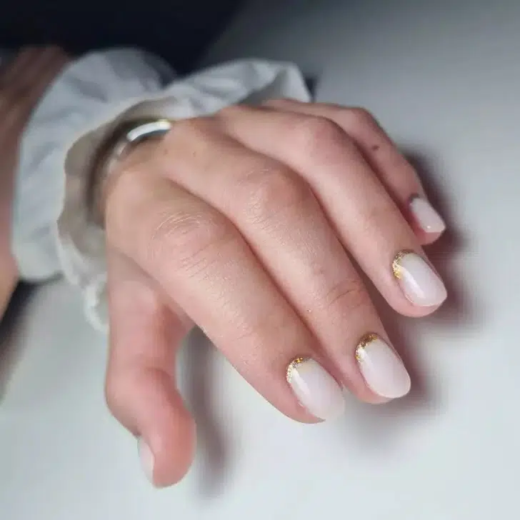 Нейтральный маникюр с золотыми блесками у основания на овальных коротких ногтях