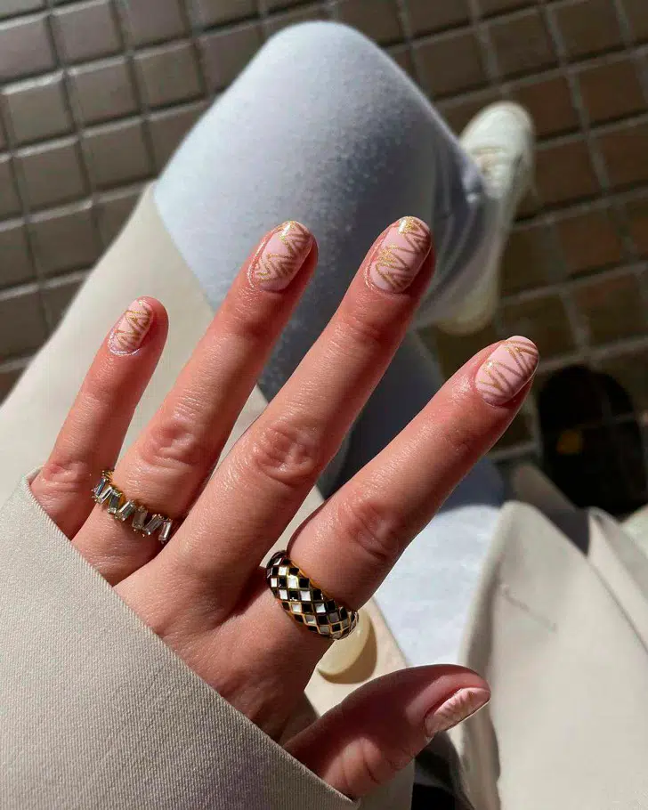Розовый маникюр с золотыми геометрическими узорами на овальных ногтях