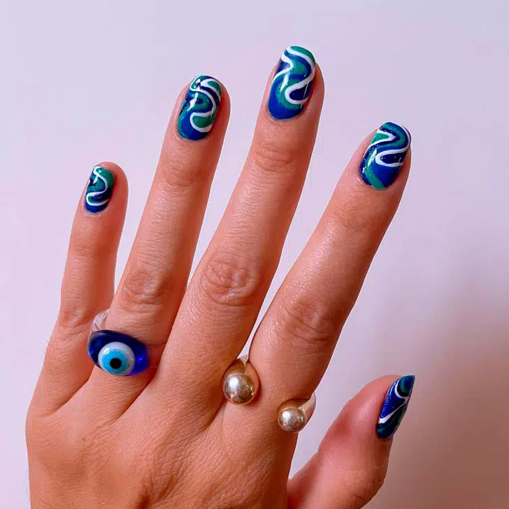Синий маникюр с завитками на овальных ногтях средней длины