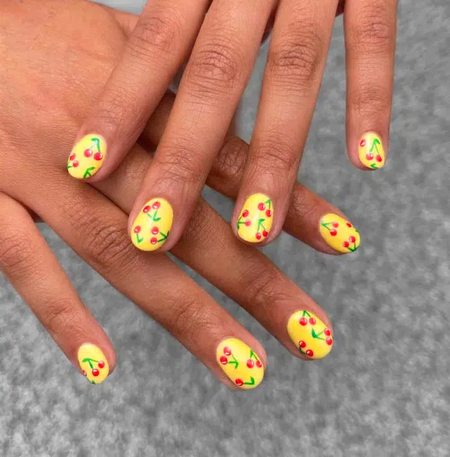 Желтый маникюр с вишнями на коротких овальных ногтях