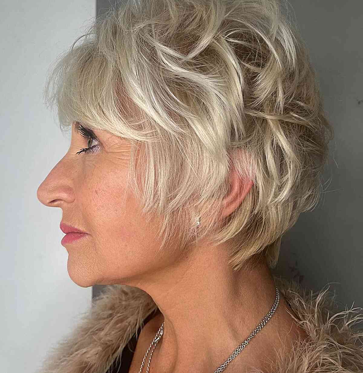 Женщина со стрижкой пикси с перьями и челкой на тонких светлых волосах
