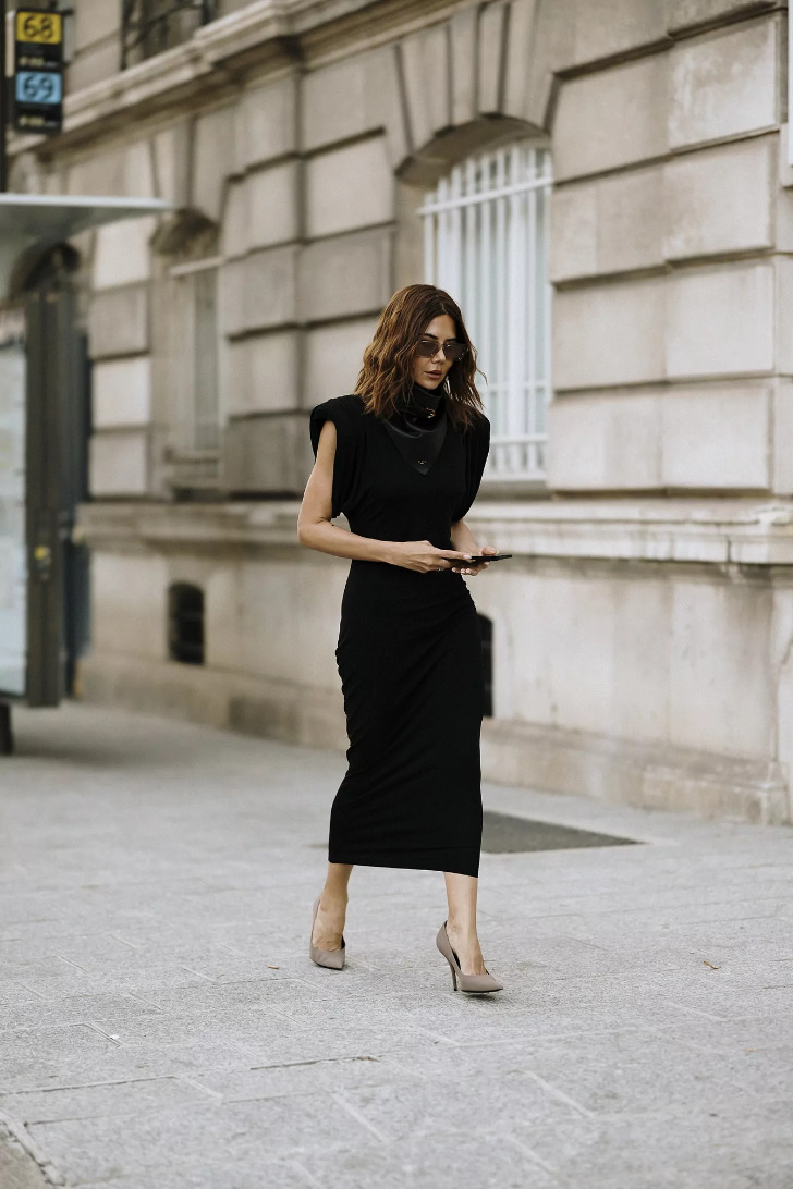 Девушка в облегающем черном платье миди и нейтральных туфлях на шпильке