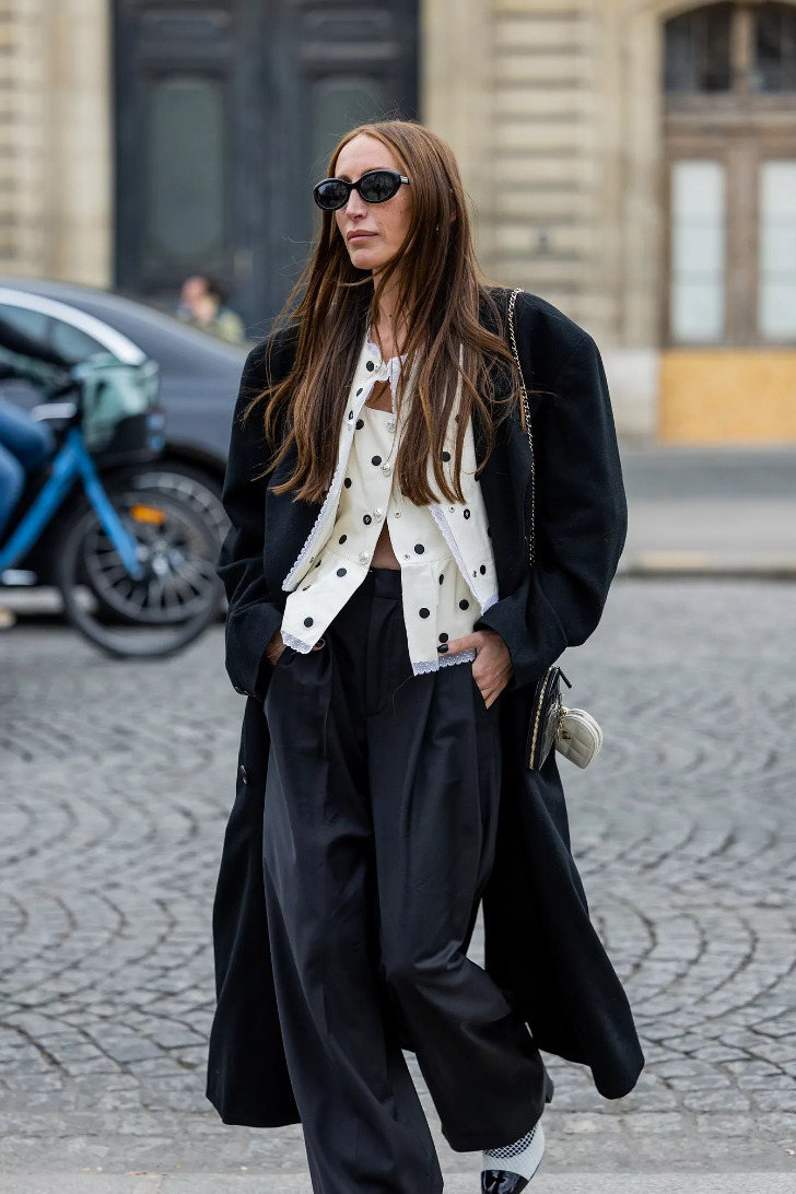 Девушка в широких брюках, белой блузке в горох и черном пальто