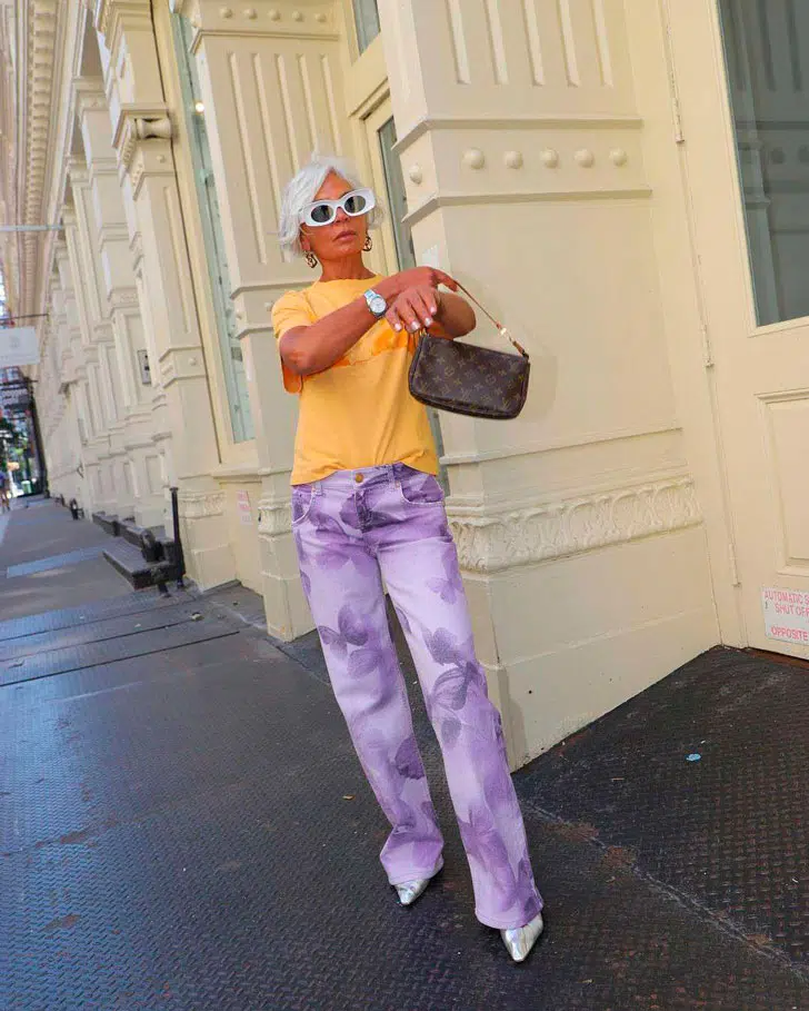 Грес Ганем в фиолетовых брюках с принтом, желтой футболке и туфлях на каблуке
