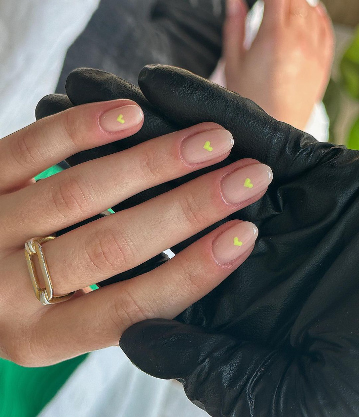 Нейтральные ногти с желтыми сердечками на овальных ухоженных ногтях