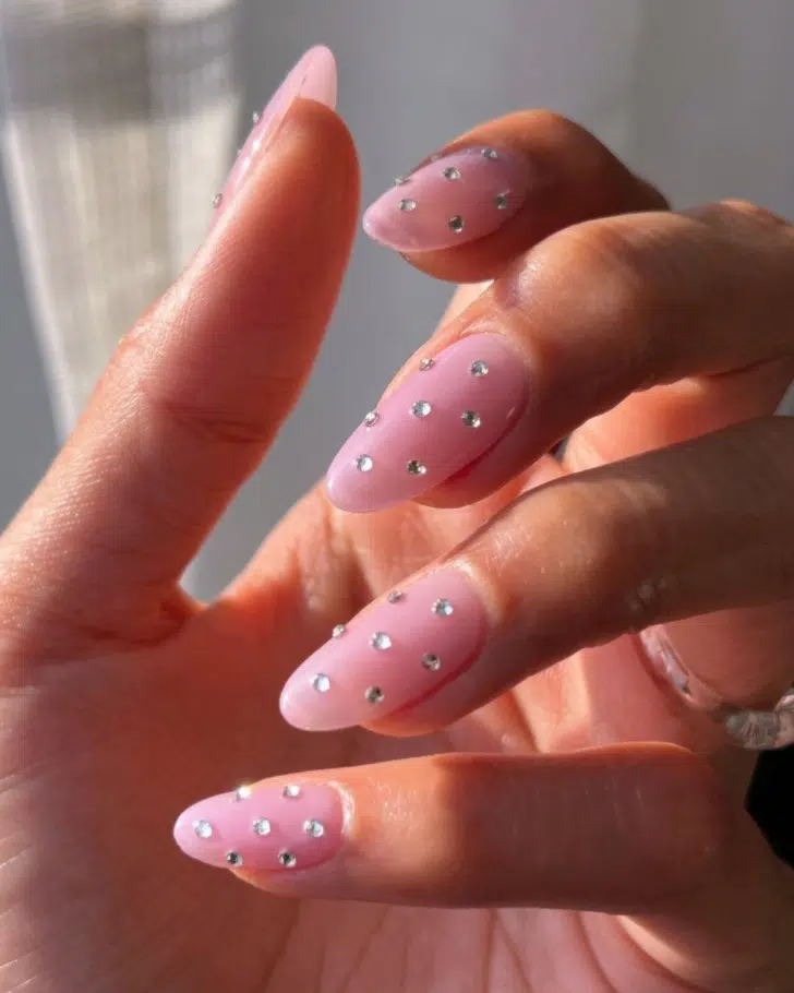 Розовый маникюр со стразами на ухоженных овальных ногтях средней длины