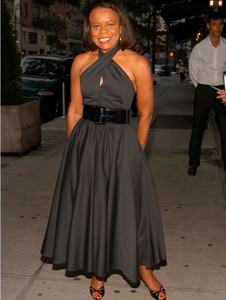 Женщина в черном вечернем платье с широким поясом и босоножках