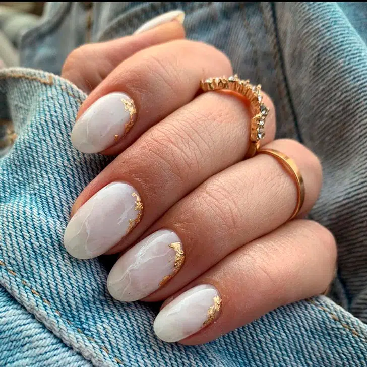 Белый мраморный маникюр с золотой фольгой на овальных ногтях средней длины