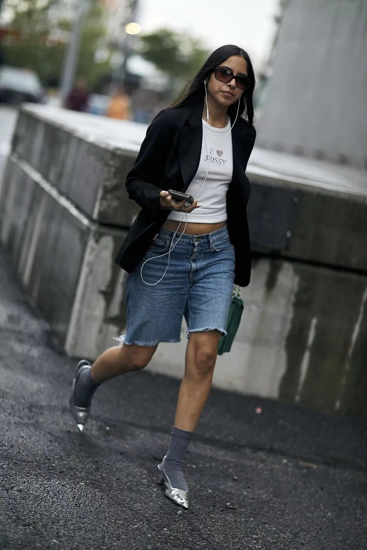 Девушка в джинсовых шортах, черном жакете и серебристых туфлях с носками