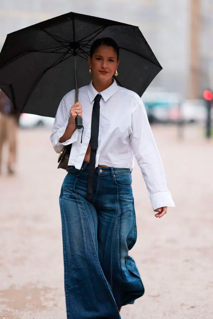 Девушка в мешковатых джинсах и укороченной белой рубашке с галстуком