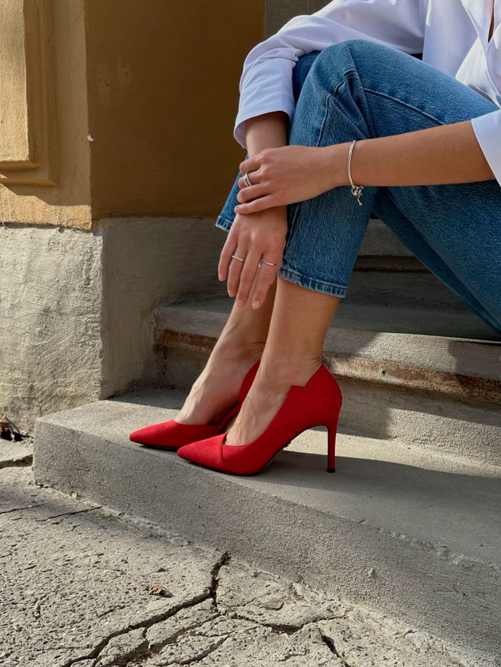Девушка в укороченных джинсах, классической рубашке и красных туфлях на шпильке