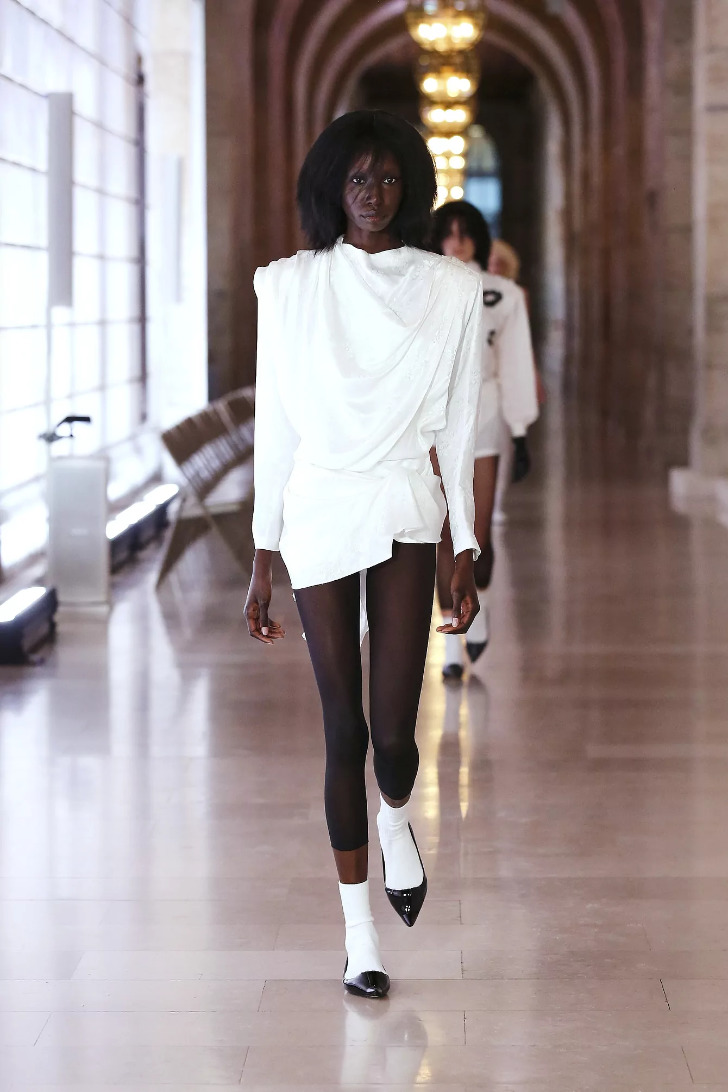 Модель в белом мини платье и черных балетках с белыми носками от Marc Jacobs