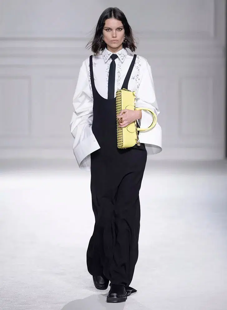 Модель в черном сарафане макси и белой рубашке с галстуком от Valentino