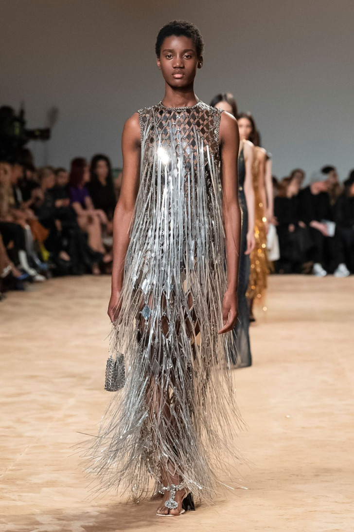 Модель в длинном платье с перьями и серебряных туфлях