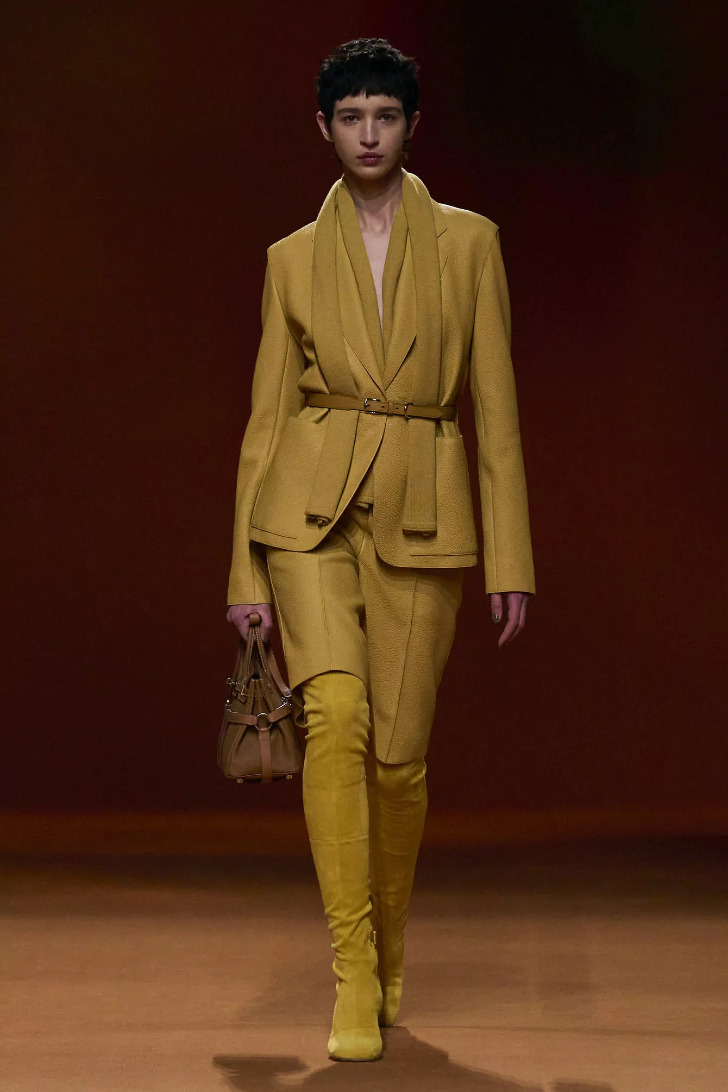 Модель в костюме горчичного цвета и поясом на жакете от Hermès