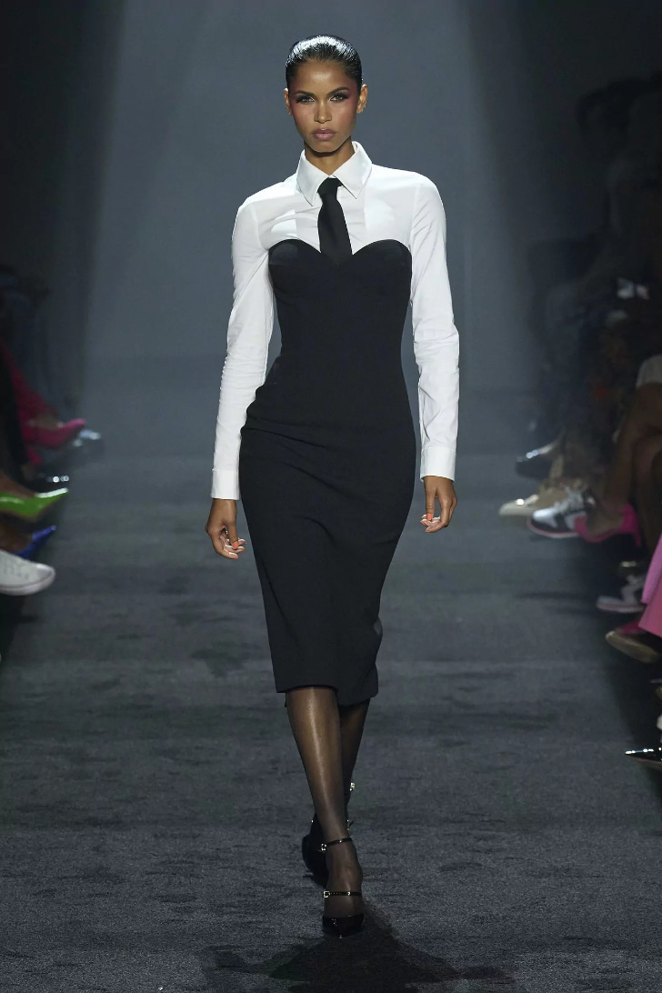 Модель в облегающем черном платье и белой рубашке с галстуком от Sergio Hudson