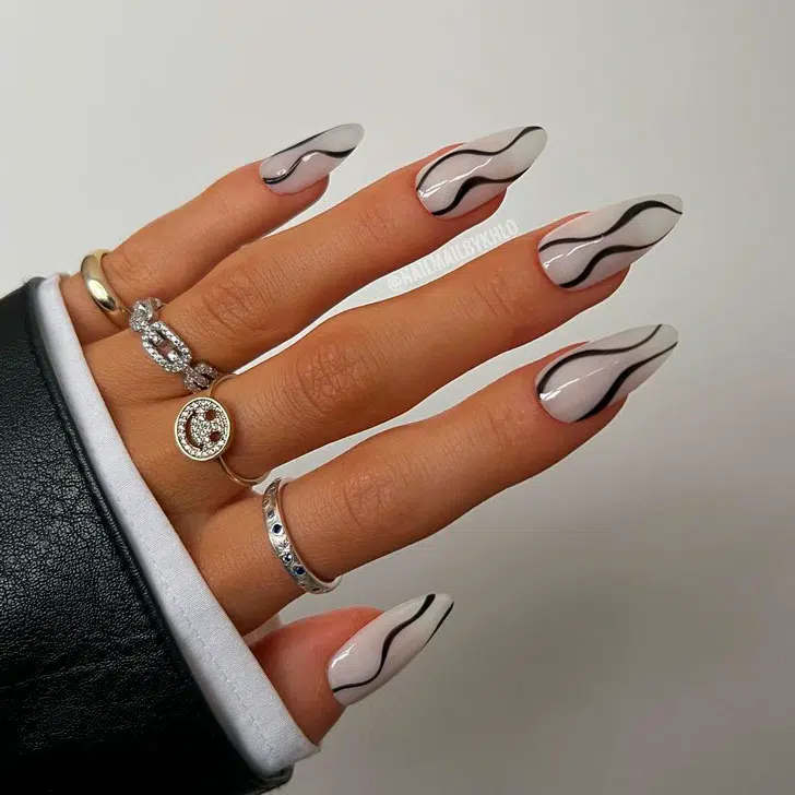 Молочный маникюр с черными завитками на длинных миндальных ногтях