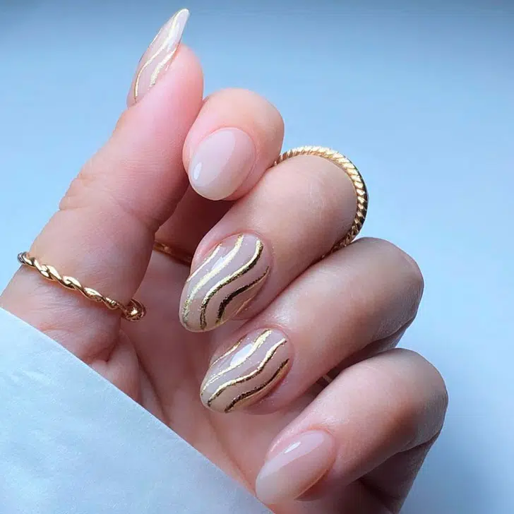 Натуральный маникюр с золотыми завитками на овальных ногтях средней длины