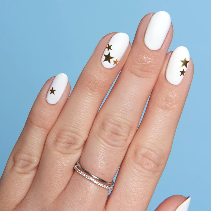 Белый маникюр с золотыми звездами на коротких овальных ногтях