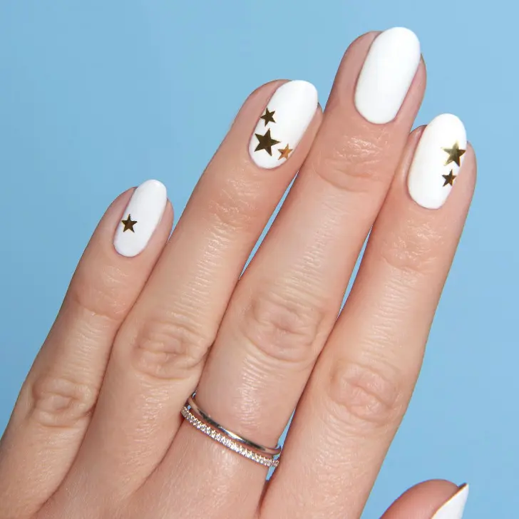 Белый маникюр с золотыми звездами на коротких овальных ногтях