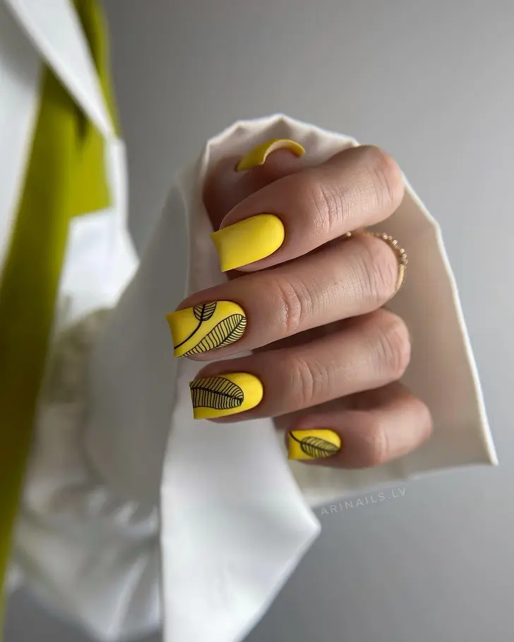 Маникюр на желтых ногтях с черными листками